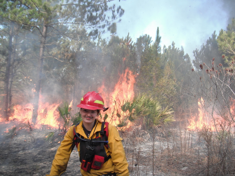 female firefighter, wildfire in background