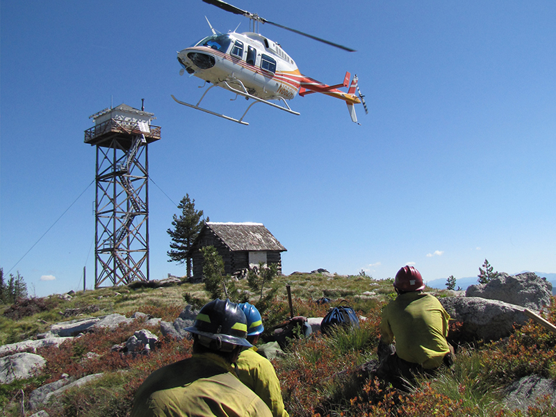 firefighters waiting for helicopter to land on mountain