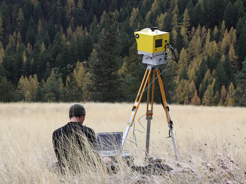 man in field with computer and equipment monitoring wildfires